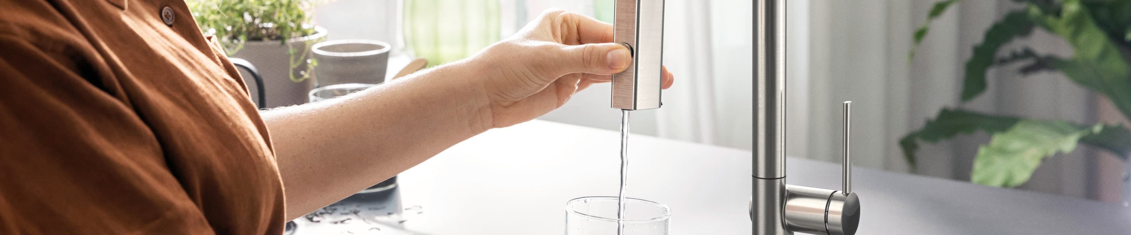 GriferÃa de cocina con filtro hansgrohe Aqittura M91 sirviendo agua filtrada